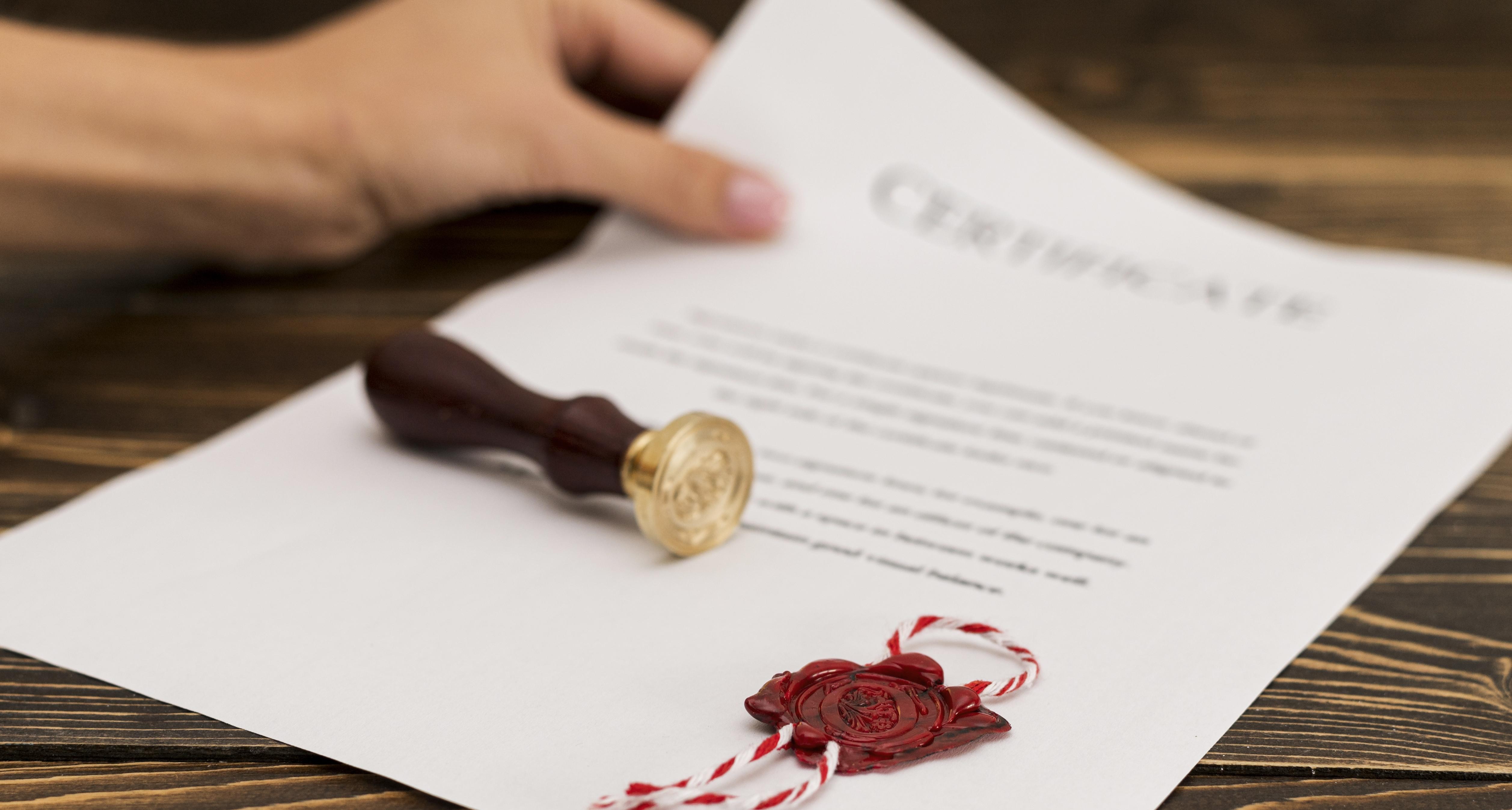 A certificate on a wooden desk with a wax seal stamp and a finished red seal