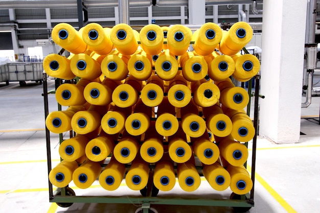 Yellow yarn spools on a mill trolley inside a textile factory